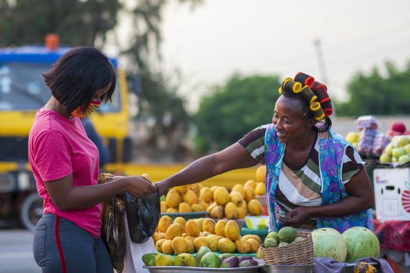 Cliente choisissant des fruits et légumes frais sur un étal de marché au Cameroun